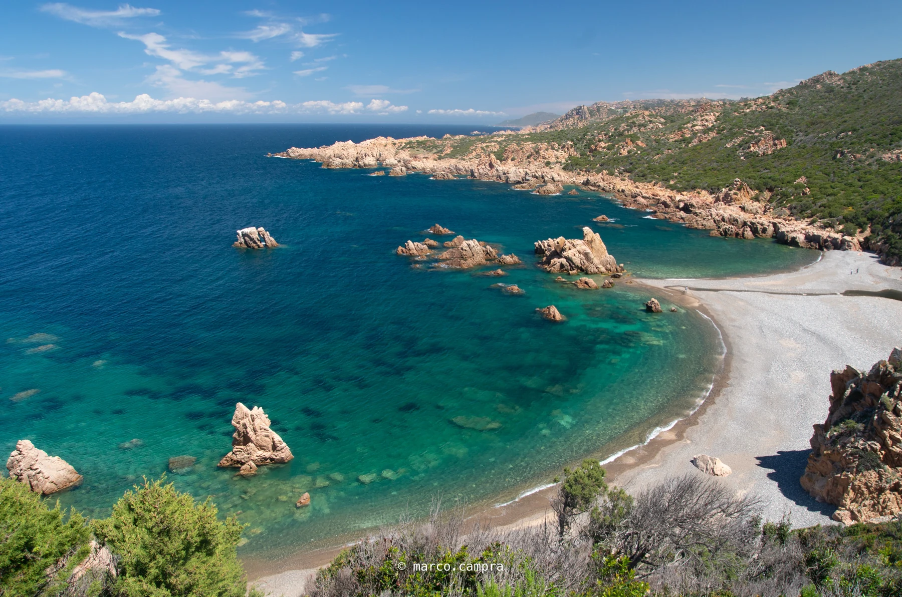 Tinnari: cala selvaggia e mare turchese La cala di Tinnari vista dall’alto, con spiaggia di ciottoli, granito rosa e mare turchese